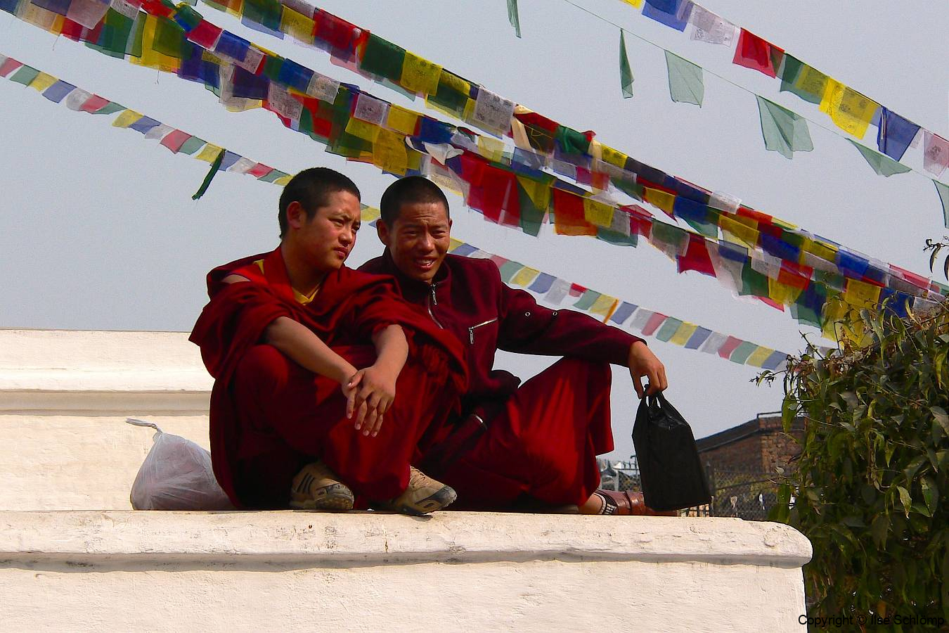 Nepal, Bodnath, Bodnath-Stupa, Buddhistische Mönche sitzen unter Gebetsfahnen