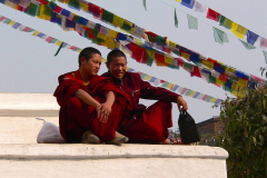 Nepal, Bodnath, Bodnath-Stupa, Buddhistische Mönche sitzen unter Gebetsfahnen